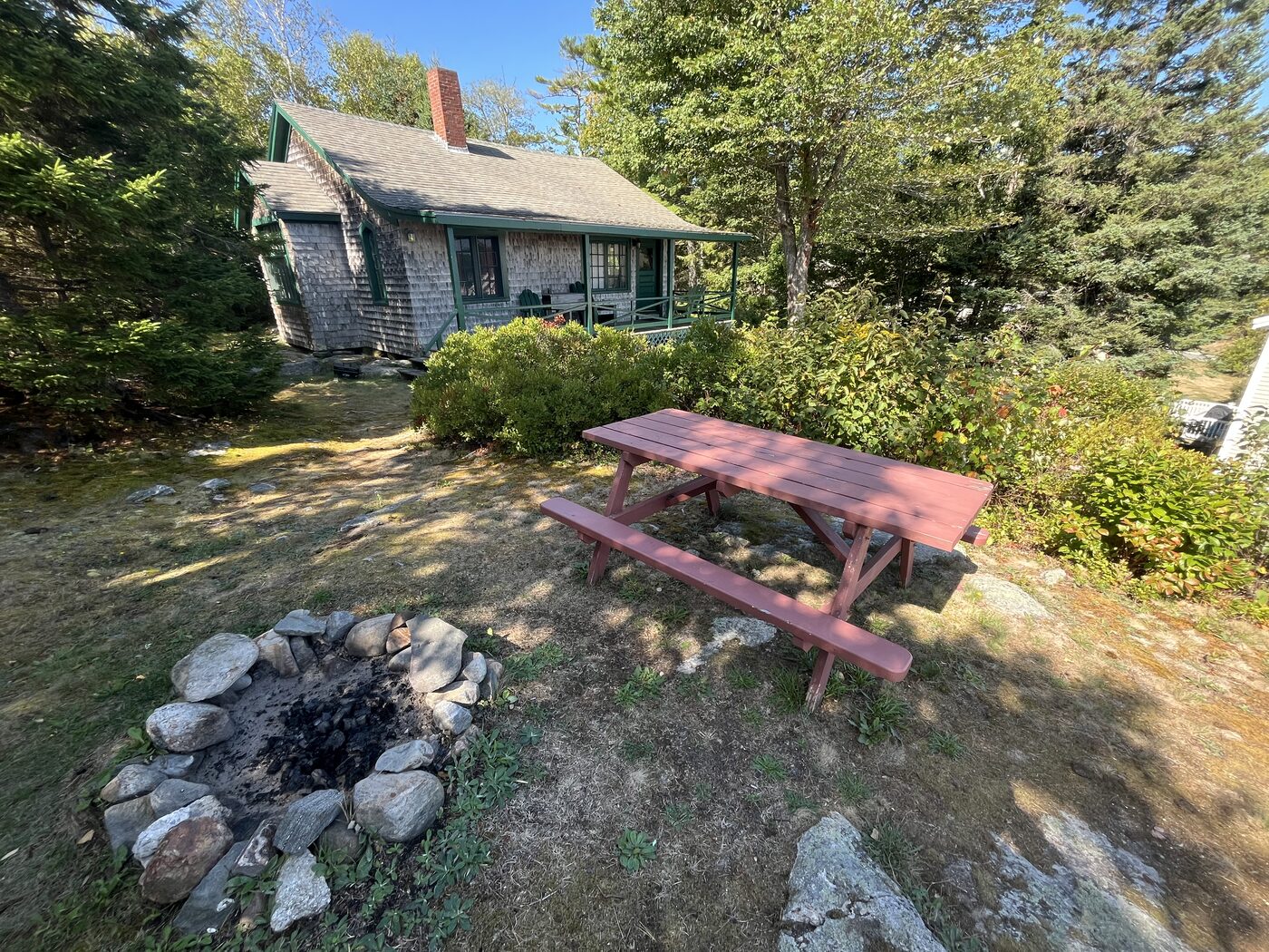 Hillside Cottage exterior with picnic table and stone fire pit