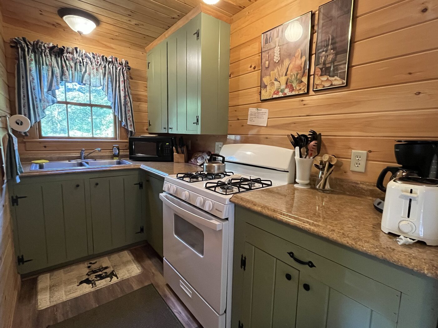 Full kitchen with green cabinetry inside Hillside Cottage