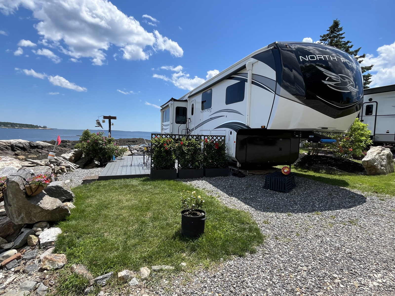Camper set up on a grassy oceanfront site along the rocky Maine coast